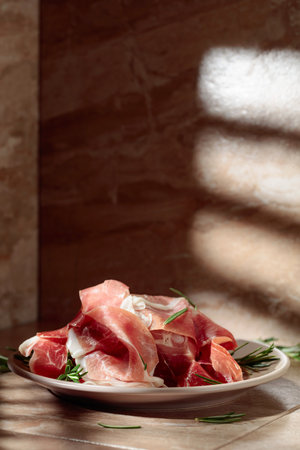 Italian prosciutto or Spanish jamon with rosemary on a kitchen table. Copy space.