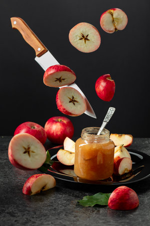 Apple jam and kitchen knife with red fresh apple slices on a black background.の写真素材