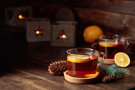 Tea with lemon and small Christmas lanterns with burning candles on a wooden table.の写真素材