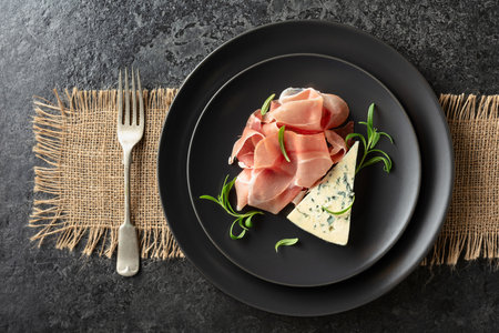 Blue cheese, prosciutto, and rosemary on a blackstone table. Top view.の写真素材
