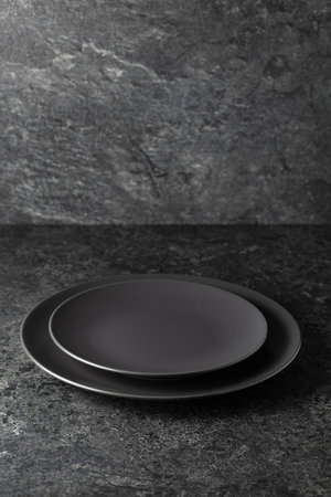 Empty round black plates on a black stone background with copy space.