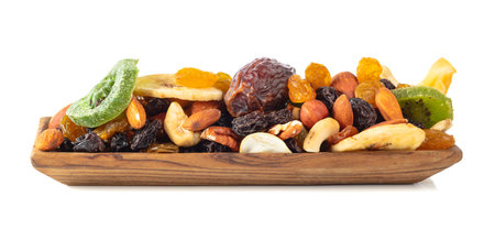 Dried tropical fruits, nuts, and raisins isolated on a white background. Dried fruits in wooden dish.の写真素材