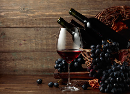 Red wine and blue grapes. Wine and grapes in a vintage setting on an old wooden table.の写真素材