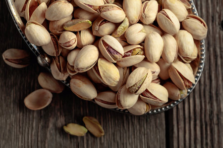 Salted pistachios in a dish on an old wooden table. Top view.