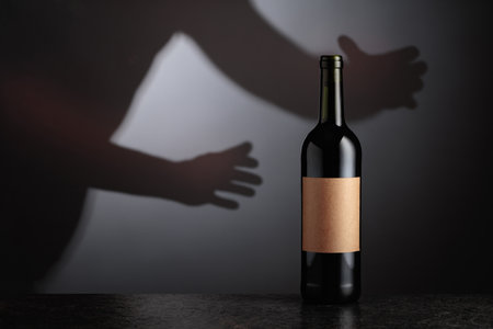 Bottle of red wine with old empty label. Hand in reaches for a bottle of red wine. Copy space.の写真素材