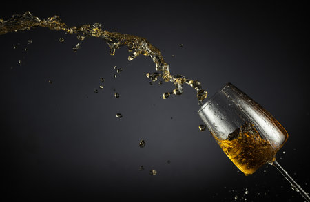Glass and white wine splash on a black background. Copy space.の写真素材