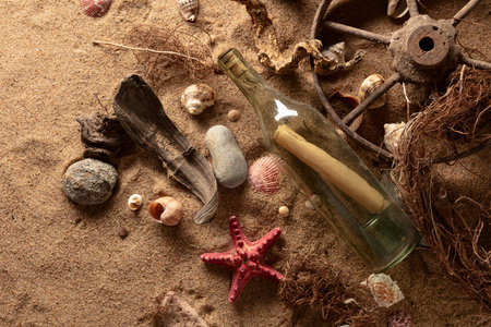 Message in a vintage bottle on a sea shore. Bottle with snags, shells, and stones on a sea sand. Top...