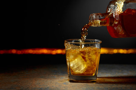 Whiskey is poured into a glass with ice. Copy space.の写真素材