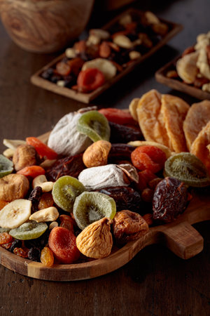 Mix of dried tropical fruits, nuts, and raisins on an old wooden table.の写真素材