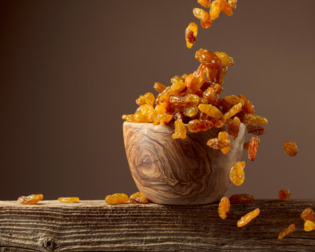 Yellow sultana raisins pour into a wooden bowl. Copy space.の写真素材