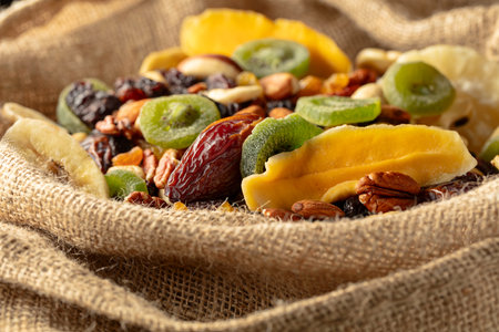 Dried tropical fruits, nuts, and raisins in burlap bag.の写真素材