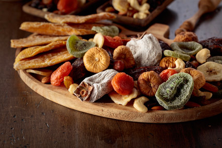 Mix of dried tropical fruits, nuts, and raisins on an old wooden table.の写真素材