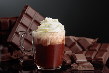 Hot chocolate with whipped cream. On a background bitter broken chocolate bar. Black reflective background with copy space.の写真素材