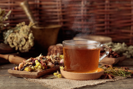 Cup of herbal tea with various dried herbs, flowers, and spices on an old wooden table. Concept of herbal medicine.の写真素材