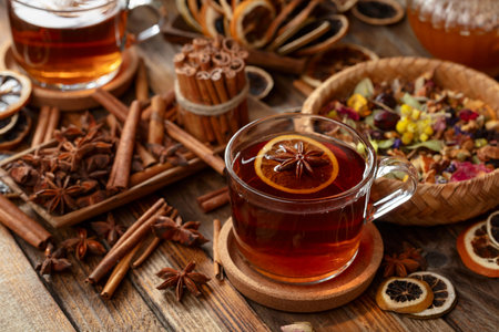 Herbal tea with cinnamon, anise, dried herbs, and dry citrus slices. Herbal tea with ingredients on an old wooden table.の写真素材