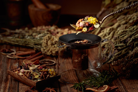 Various dried herbs and spices are poured into a glass teapot. Aromatherapy or herbal medicine concept.の写真素材