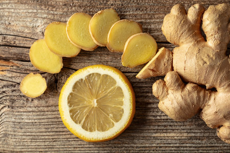 Fresh ginger root and lemon slice on an old wooden board. Top view.の写真素材
