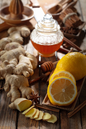 Ingredients for preparing ginger tea. Ginger, lemon, honey, anise, and cinnamon sticks on an old kitchen table.の写真素材
