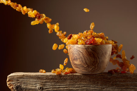 Yellow sultana raisins pour into a wooden bowl. Copy space.の写真素材