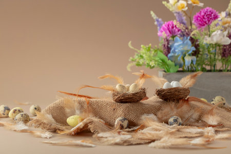 Easter composition with eggs, delicate feathers, and spring flowers on a beige background. Lightness and freshness of spring. Free space for text or logo.の写真素材