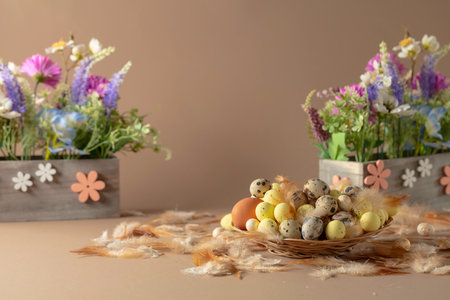 Easter composition with eggs, delicate feathers, and spring flowers on a beige background. Lightness and freshness of spring. Free space for text or logo.の写真素材