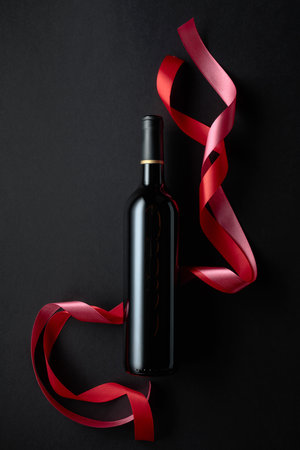 Bottle of red wine with red satin ribbons. Top view. Copy space.の写真素材