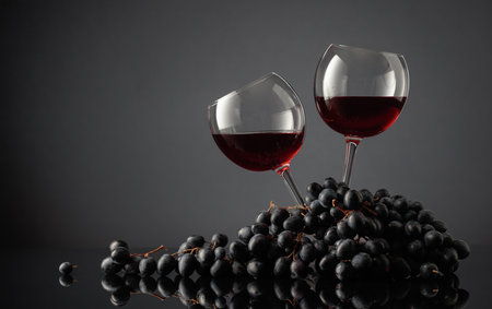 Glasses of red wine and blue grapes on a black background. Copy space.の写真素材