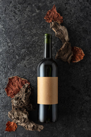 Bottle of red wine on a black stone background. Red wine, old snags, and dried vine leaves. Top view. Copy space.の写真素材