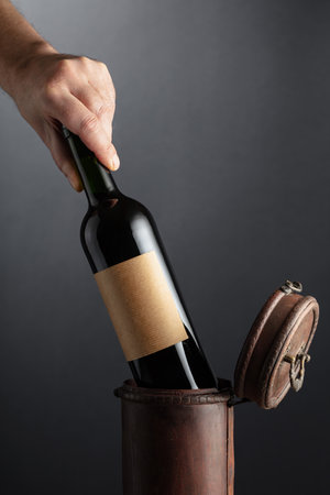 The sommelier places a bottle of red wine in an old wooden box. On a bottle label. Copy space.の写真素材