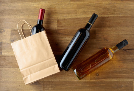 Bottles of wine and a paper bag on a wooden background. Top view. Place your logo or text on the paper bag or in the copy space.の写真素材