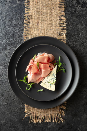 Blue cheese, prosciutto, and rosemary on a table. Top view.の写真素材