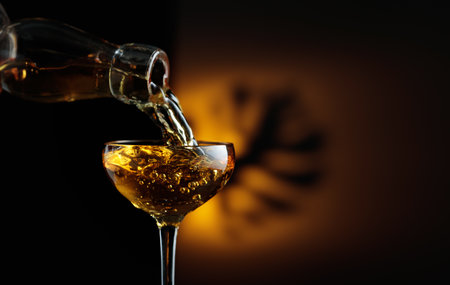 Rum being poured from a bottle into a glass. On a background shadow of palm leaf. Copy space.の写真素材
