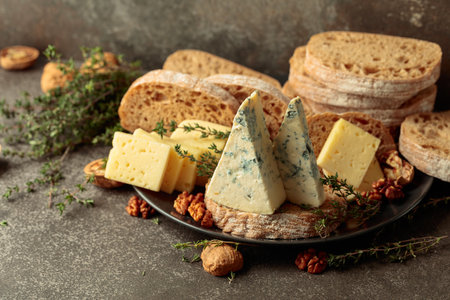 A rustic spread of cheese, bread, walnuts, and thyme on a stone kitchen table, where simple ingredients create a moment of warmth and timeless comfort.の写真素材