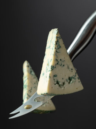 A cheese knife cuts a piece of blue cheese in half.の写真素材