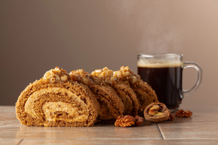 Walnut and buttercream roll: a traditional pastry. Dessert with walnuts and coffee on a beige background. Cake with brown sugar, walnuts, and cream. Copy space.の写真素材