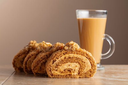 Walnut and buttercream roll: a traditional pastry. Dessert with walnuts and coffee latte on a beige background. Cake with brown sugar, walnuts, and cream. Copy space.の写真素材