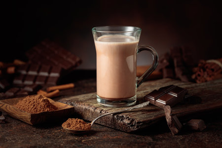 Creamy hot chocolate drink on a brown background. A mug of hot chocolate with broken bitter chocolate bars and cocoa powder. Copy space.の写真素材