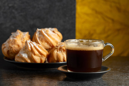 Black coffee in glass cup and cream cakes on a black stone table. Copy space.の写真素材