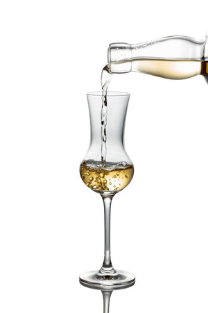 Gold liquor pouring into a glass. Isolated on a white background.の写真素材