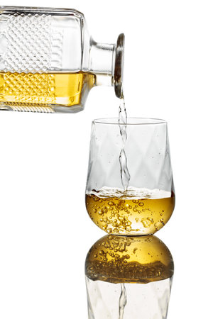Pouring whiskey from a decanter into a glass. Isolated on a white background.の写真素材