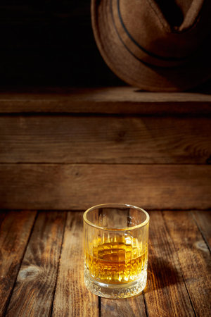 Elegant whiskey glass filled with amber liquid on an old wooden table. Copy space.の写真素材