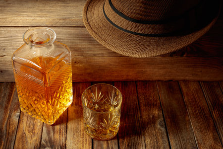 Elegant whiskey glass and decanter filled with amber liquid on an old wooden table. Copy space.の写真素材