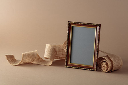 Empty picture frame and burlap ribbon on beige background. Place your image in the frame. Copy space.の写真素材