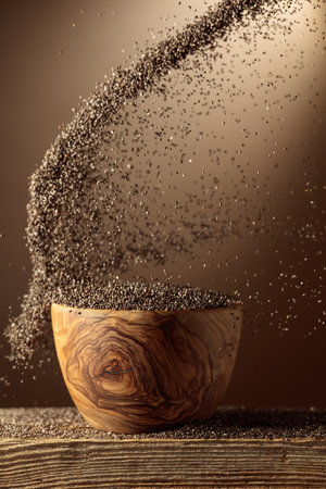 Chia seeds are poured into a wooden bowl. Beige background with copy space.の写真素材
