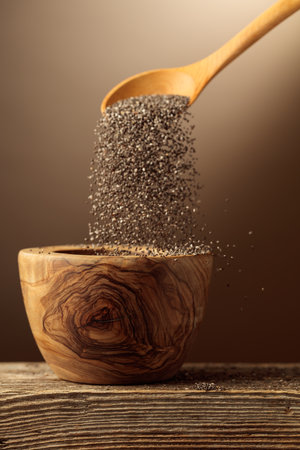 Chia seeds are poured into a wooden bowl.の写真素材