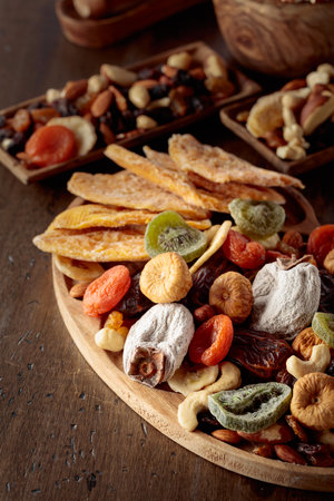 Mix of dried tropical fruits, nuts, and raisins on an old wooden table.の写真素材
