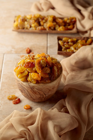 Yellow sultana raisins in a wooden bowl on a beige background. Copy space.の写真素材