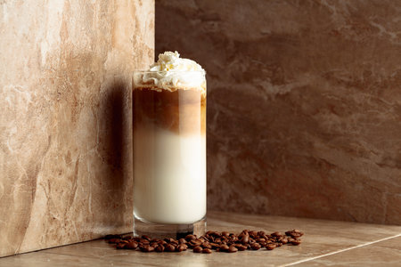 Milk coffee cocktail on a beige ceramic table with coffee beans. Copy space.の写真素材