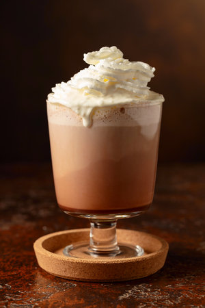 Hot chocolate with whipped cream in a glass mug on an old brown table. Copy space.の写真素材