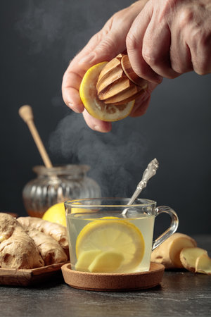 Ginger tea with lemon and honey. Juice is squeezed out of a lemon with an old wooden juicer.の写真素材